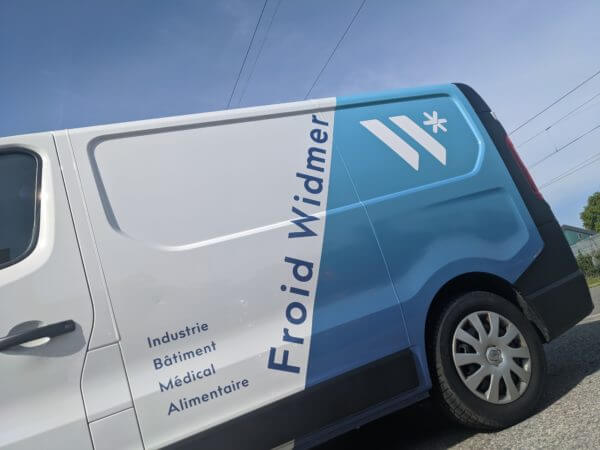 Camionnette Froid Widmer sur route, ciel bleu.