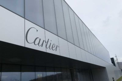 Façade vitrée moderne du bâtiment Cartier avec logo discret en lettrage noir sur panneau métallique clair