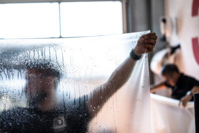 Pose de film de protection transparent sur vitre.