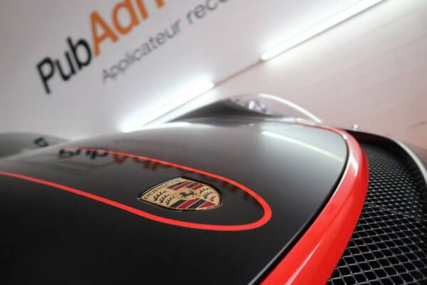 Logo automobile sur capot noir et rouge.