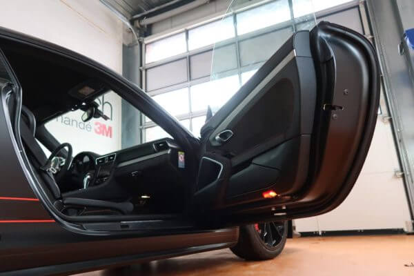 Porte de voiture sportive ouverte dans un garage.