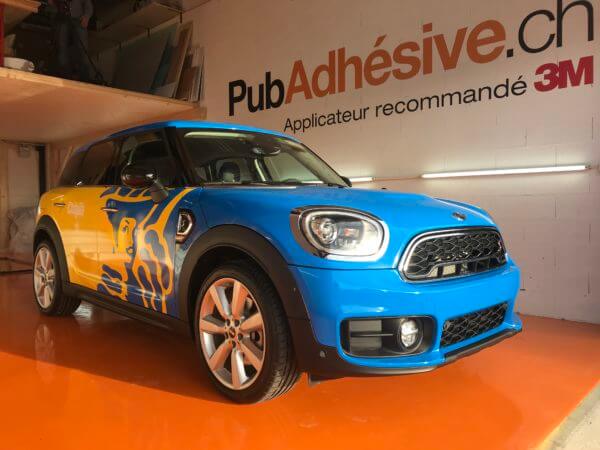 Voiture bleue avec publicité adhésive intérieure.