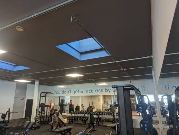 Salle de gym avec équipements et haltères, slogan motivant.