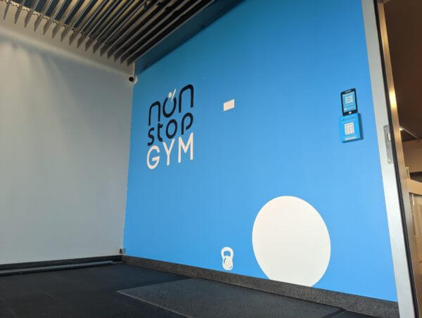 Entrée de gym avec logo Non-Stop, mur bleu.
