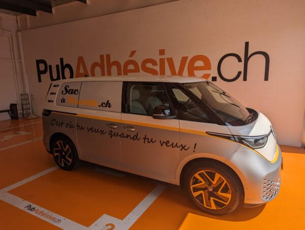 Fourgon publicitaire dans un garage orange.