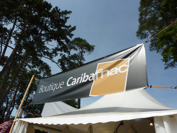 Panneau Boutique Caribafnac sous les arbres.
