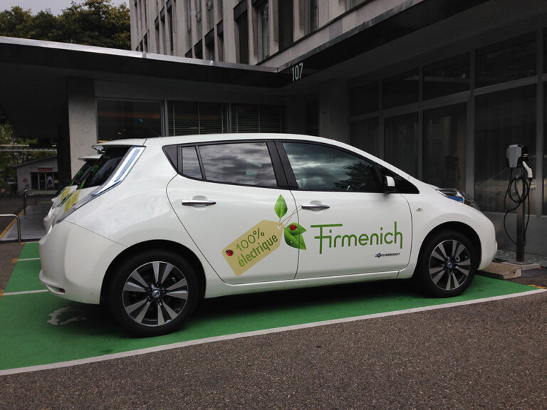 Voiture électrique blanche en charge sur parking.