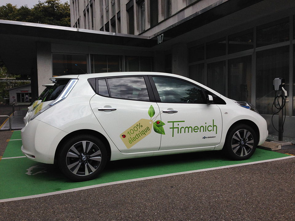 Voiture électrique blanche en charge sur parking.