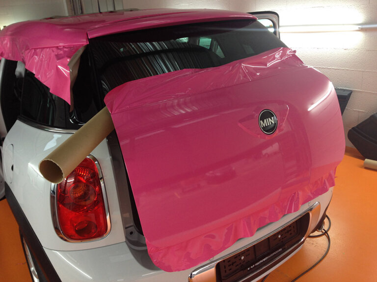 Voiture blanche enveloppée de film rose.