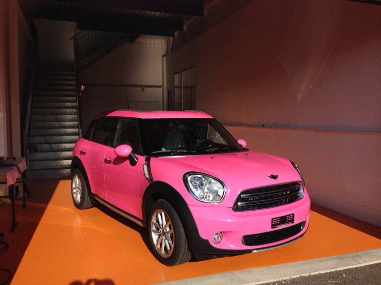 Voiture rose garée dans un garage.