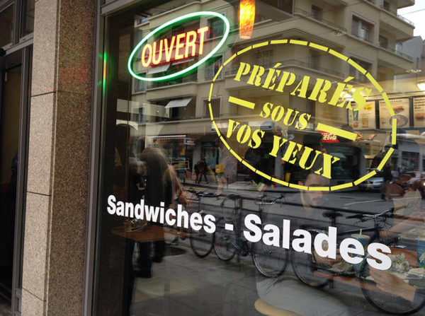 Devanture de café avec enseigne 'Ouvert'.