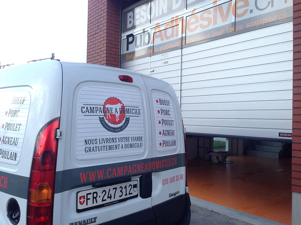 Camionnette Campagne à Domicile devant un entrepôt.