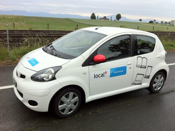 Petite voiture blanche au bord de la route.