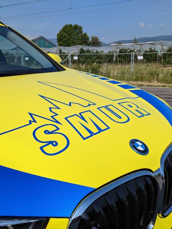 Voiture SMUR jaune et bleue stationnée.