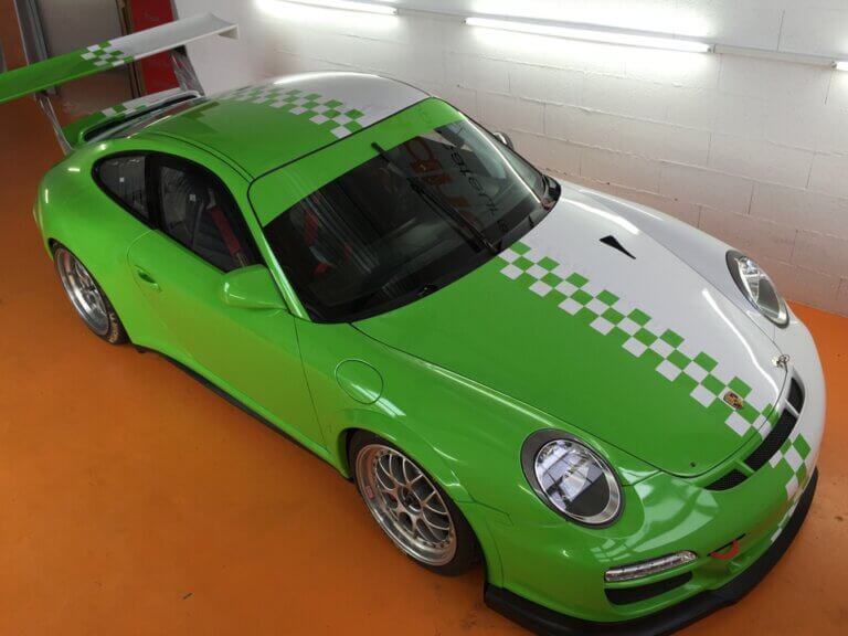 Voiture sport verte et blanche dans un garage.
