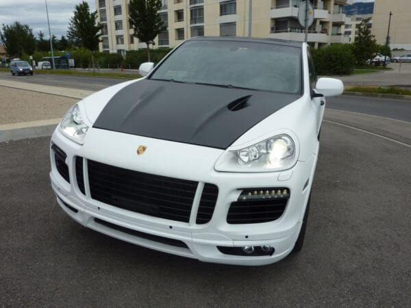 SUV blanc et noir stationné devant immeubles.