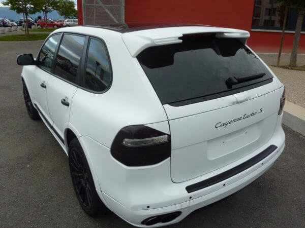 SUV blanc garé près d'un bâtiment rouge.