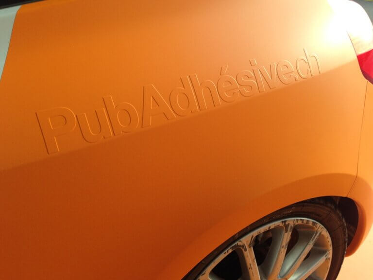 Voiture orange avec logo discret sur la carrosserie.