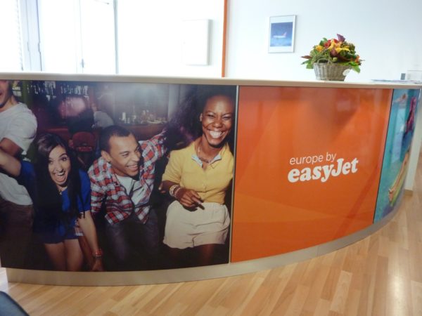 Bureau avec affiches easyJet et personnes souriantes.