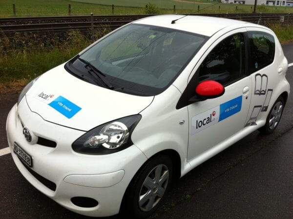 Voiture blanche avec logos d'entreprise de livraison.