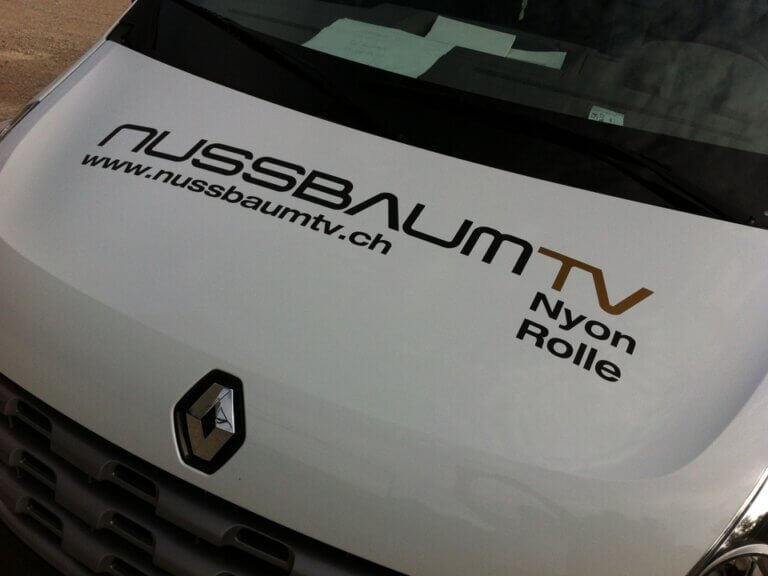 Logo Nussbaum TV sur capot de voiture Renault.