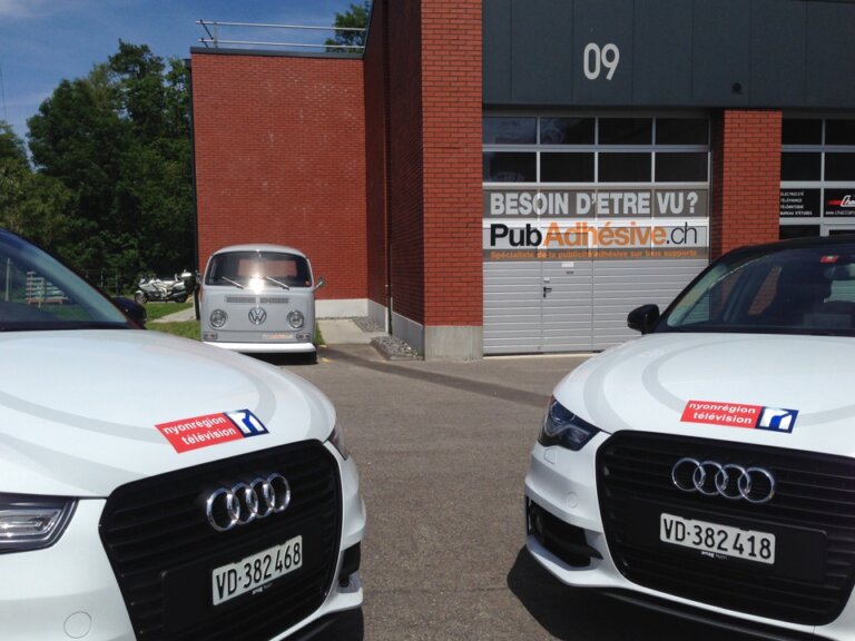 Voitures et van devant entreprise de publicité.