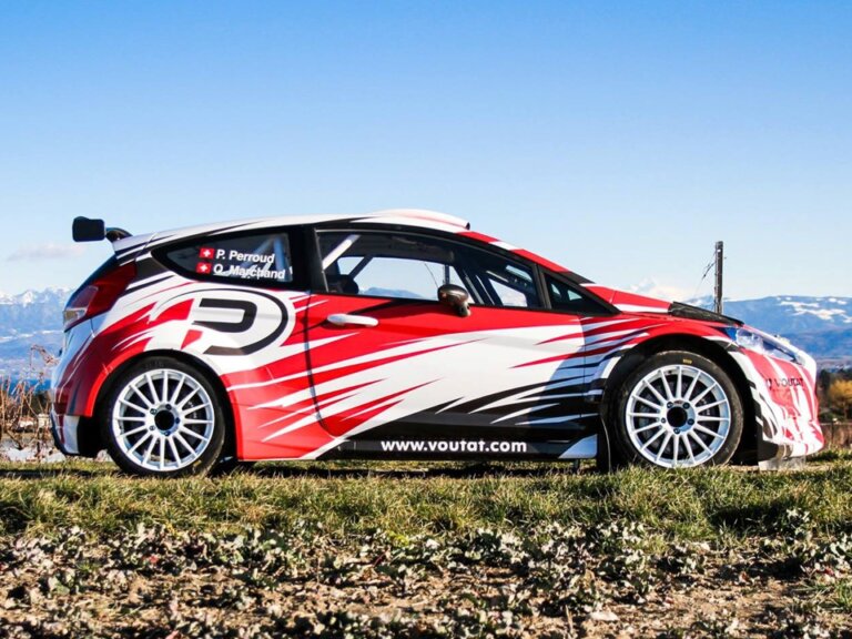 Voiture de rallye rouge et blanche sur fond montagneux.