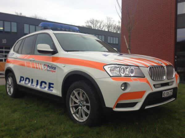 SUV de police blanche stationnée devant un bâtiment.