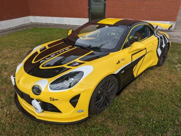 Voiture de course Alpine jaune et noire stationnée.