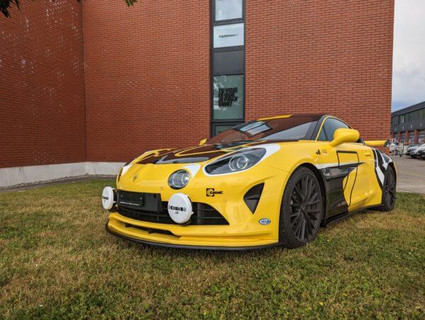 Voiture jaune garée devant un bâtiment en brique.