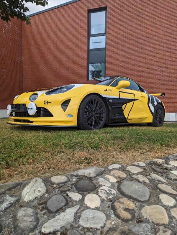 Voiture jaune sportive garée devant un bâtiment.