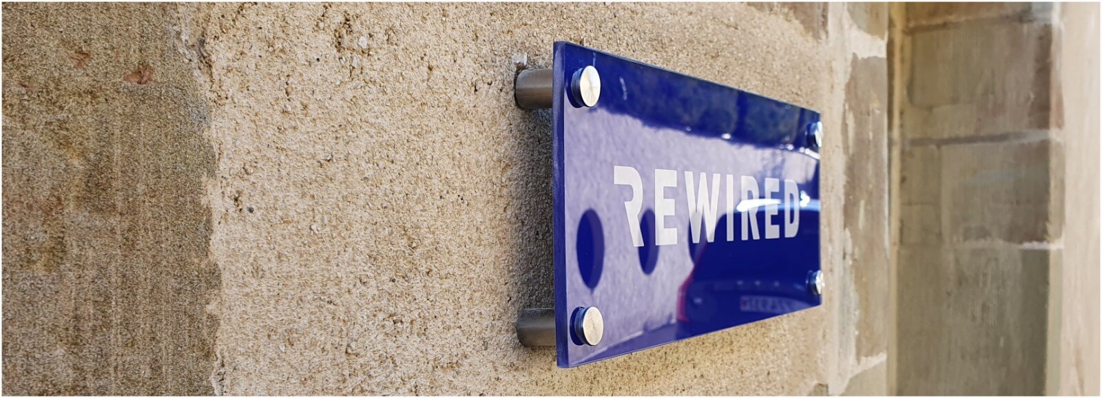 Plaque bleue avec le mot 'Rewired'.