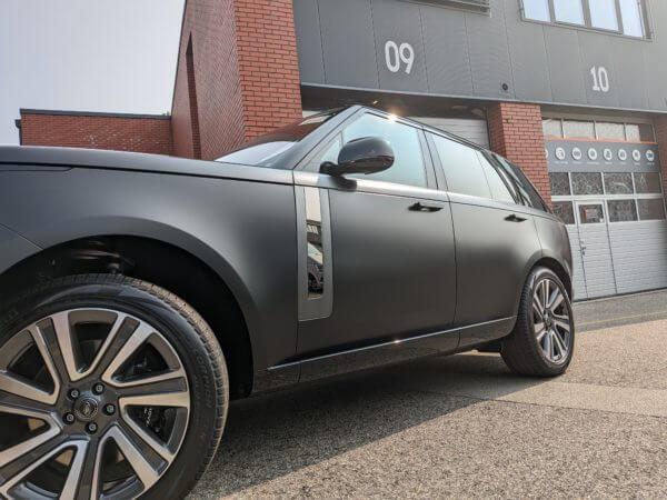 SUV noir devant immeuble industriel.