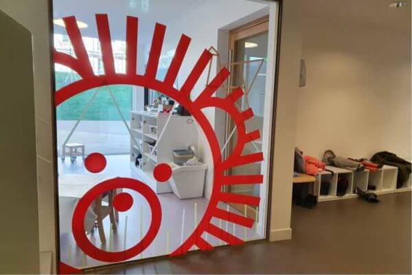 Salle de jeux pour enfants avec motif rouge sur vitre.