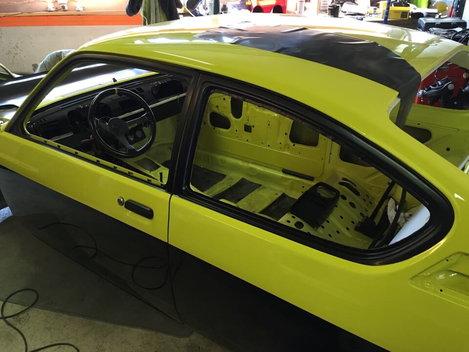 Carrosserie d'une voiture jaune en cours de restauration.