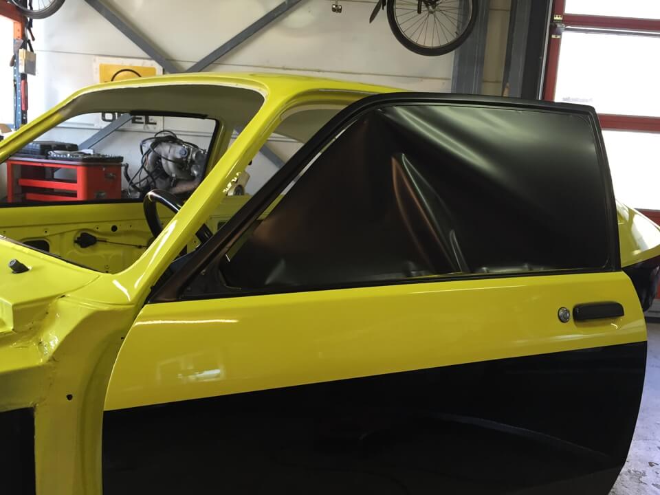 Voiture jaune en cours de rénovation dans un garage.
