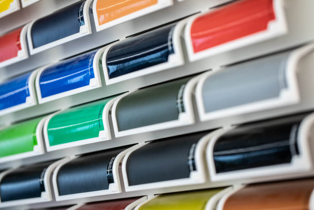 Échantillons de vinyle coloré sur étagères blanches.