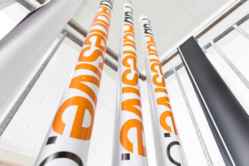 Affiches publicitaires orange alignées verticalement.