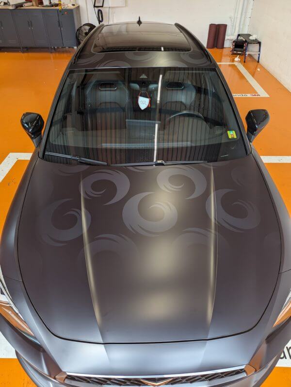 Voiture grise avec motifs sur le capot.