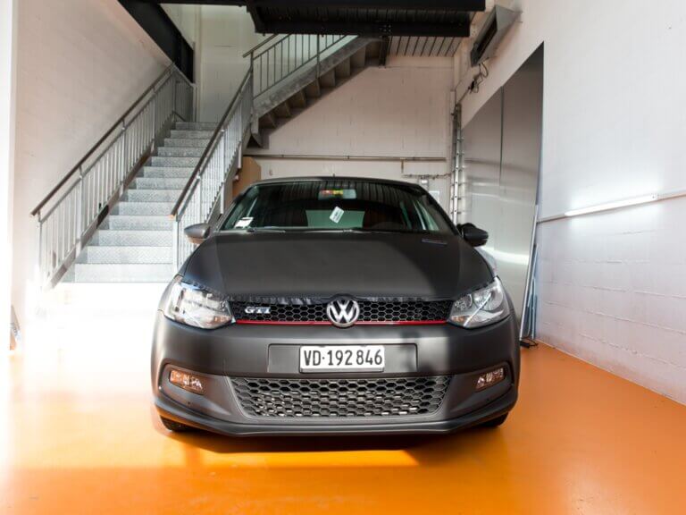 Voiture noire Volkswagen garée dans un garage lumineux.